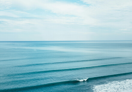A scenic landscape of a vast blue ocean on a blue sky day